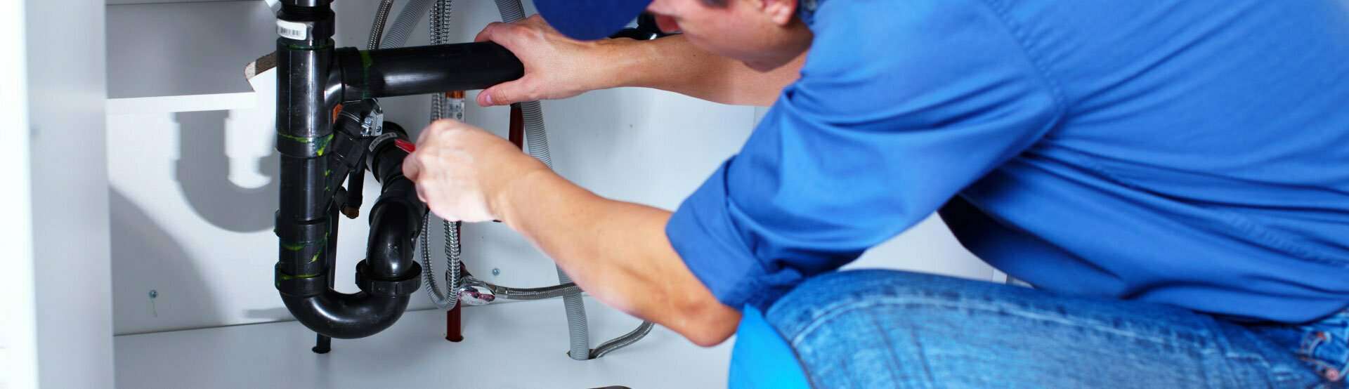 Plumber under sink repairing a blockage