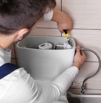 Plumber tightening a bolt in a toilet cistern