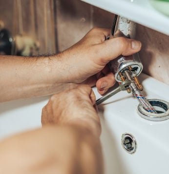 Close up of hands with tools working on a pipe