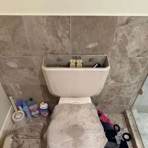 Toilet cistern opened for repair with tools and replacement seals beside it in Essendon